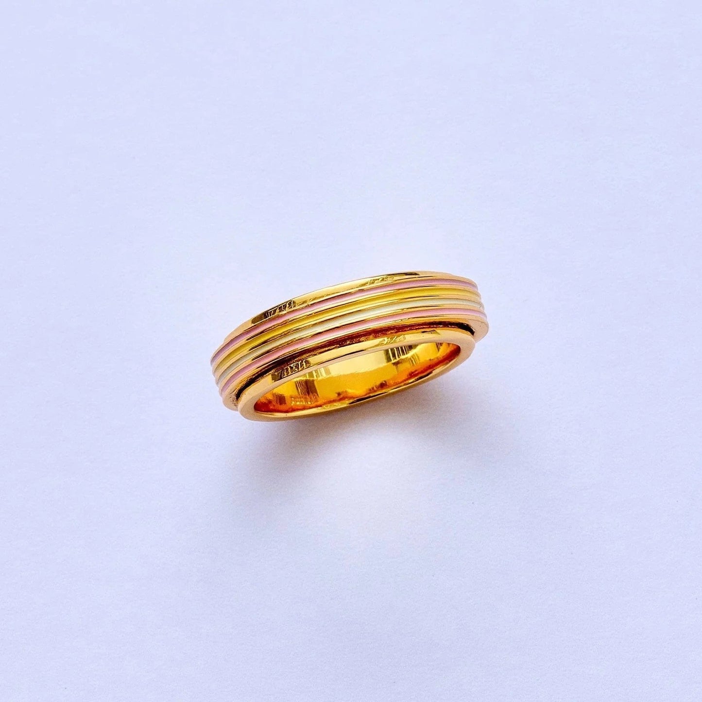 Gold ring with three bands on a light purple background