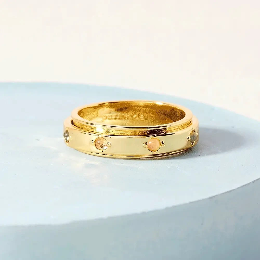 Gold ring with embedded stones on a light blue background