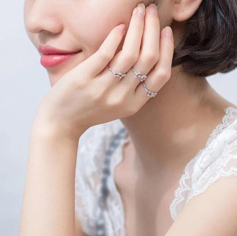 Woman wearing silver earrings with a neutral background(Zodiac ring)