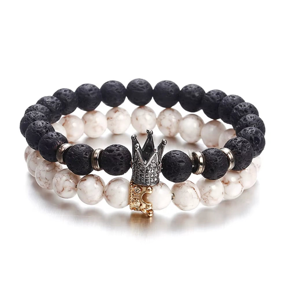 Stack of black and white beaded bracelets with a crown charm on a white background
