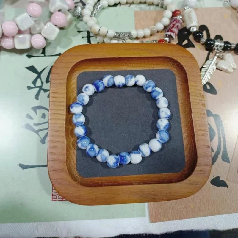 Blue and white beaded bracelet on a wooden tray with other bracelets in the background.