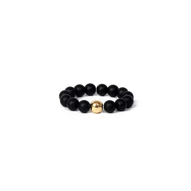 Black beaded ring with a gold accent on a white background