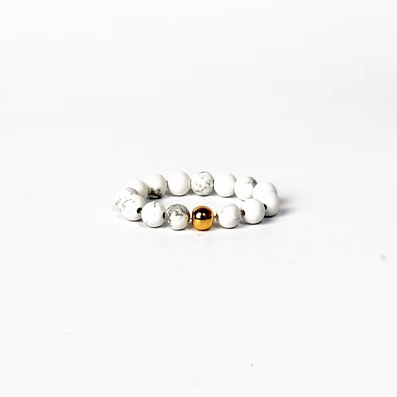 Stack of white beaded ring with a gold and silver bead on a white background