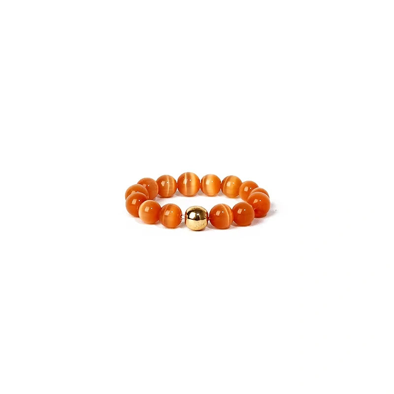 ring with orange beads and a gold accent on a white background