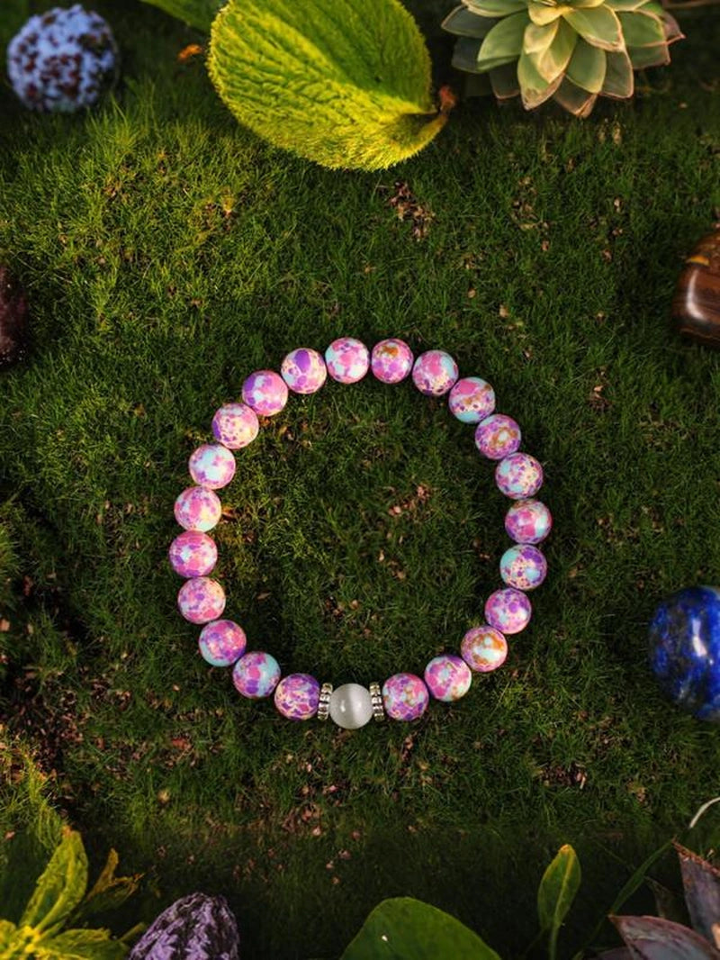 Pink beaded bracelet on a green moss background with plants