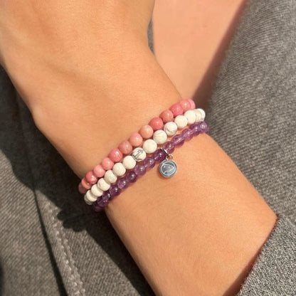 Close-up of a wrist wearing two beaded bracelets on a gray background