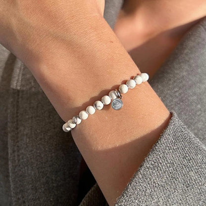 Close-up of a wrist wearing a beaded bracelet with a small round charm.