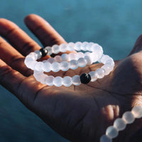 White beaded necklace held in a hand with a blurred blue background