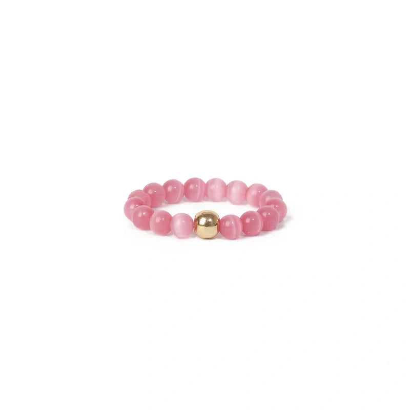 Pink beaded ring with a gold accent on a white background