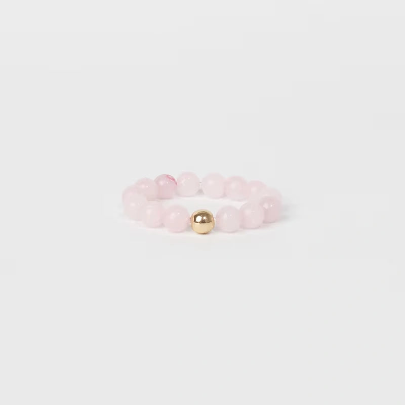 Pink beaded ring with a gold accent on a light gray background