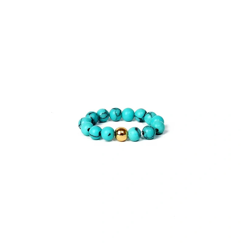 Turquoise beaded ring with a gold accent on a white background