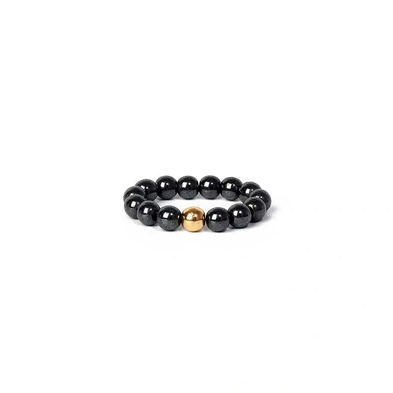 Black beaded ring with a gold accent on a white background