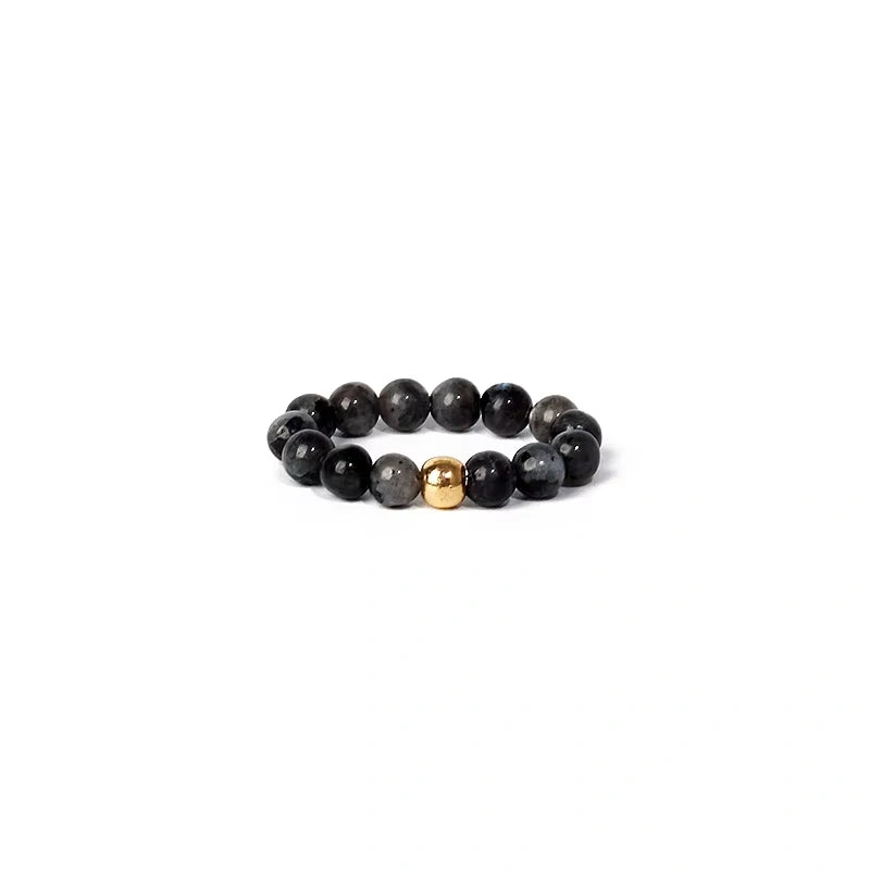Black beaded ring with a gold accent on a white background