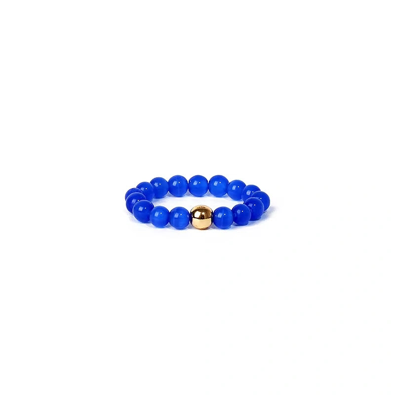 Blue beaded ring with a gold accent on a white background