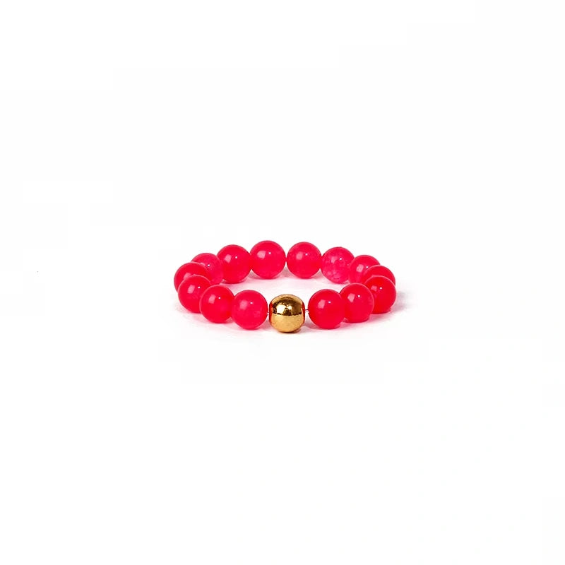 Pink beaded ring with a gold bead on a white background