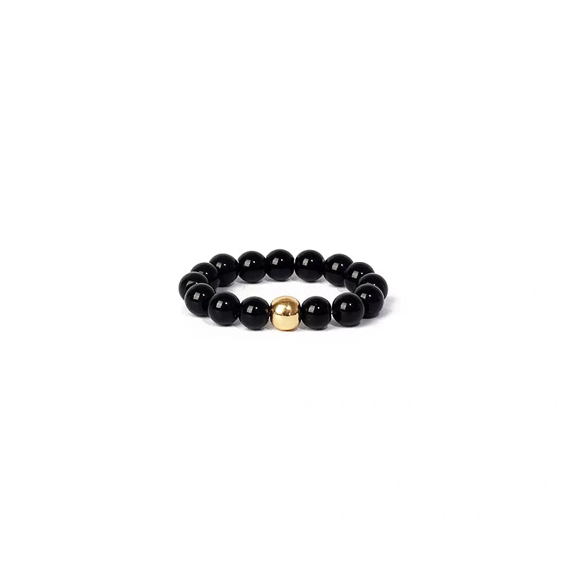 Black beaded ring with a gold accent on a white background