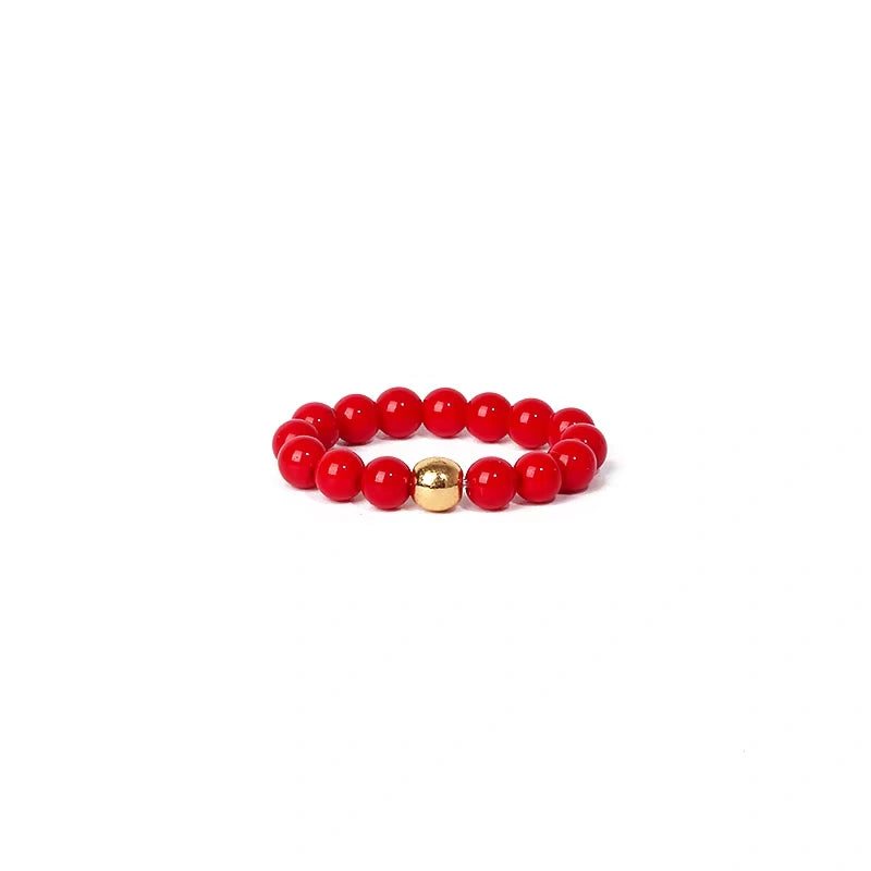 Red beaded ring with a gold charm on a white background